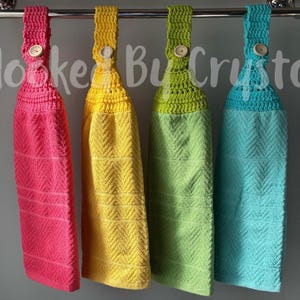 Pode incluir: Quatro toalhas de cozinha penduradas nas cores rosa choque, amarelo, verde-lim&atilde;o e turquesa, cada uma com um topo de croch&ecirc; com um bot&atilde;o de madeira, suspensas numa barra de metal prateado. O texto Hooked By Crystal est&aacute; sobreposto ao centro.