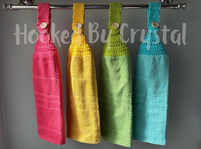 Pode incluir: Quatro toalhas de cozinha penduradas nas cores rosa choque, amarelo, verde-lim&atilde;o e turquesa, cada uma com um topo de croch&ecirc; com um bot&atilde;o de madeira, suspensas numa barra de metal prateado. O texto Hooked By Crystal est&aacute; sobreposto ao centro.