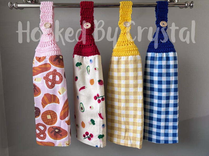 Pode incluir: Quatro panos de prato pendurados com topos de croch&ecirc; em rosa, vermelho, amarelo e azul, cada um preso com um bot&atilde;o de madeira. As toalhas apresentam padr&otilde;es de produtos de padaria, frutas e vegetais, xadrez amarelo e xadrez azul.
