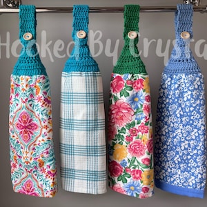 Pode incluir: Quatro panos de prato pendurados com topos de croch&ecirc; em azul-petr&oacute;leo, verde e azul, cada um preso com um bot&atilde;o de madeira. As toalhas apresentam padr&otilde;es variados, incluindo uma estampa paisley colorida, xadrez, um design floral e uma estampa floral azul.