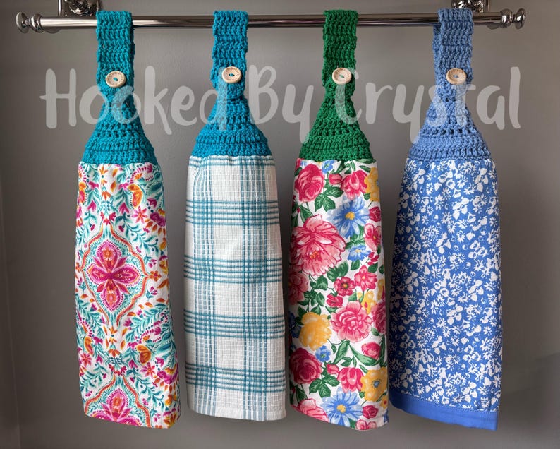 Pode incluir: Quatro panos de prato pendurados com topos de croch&ecirc; em azul-petr&oacute;leo, verde e azul, cada um preso com um bot&atilde;o de madeira. As toalhas apresentam padr&otilde;es variados, incluindo uma estampa paisley colorida, xadrez, um design floral e uma estampa floral azul.