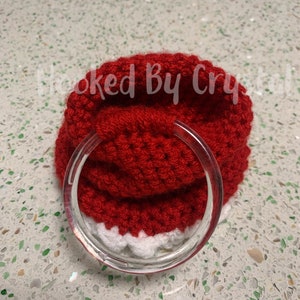 Puede incluir: Un gorro de Pap&aacute; Noel de punto rojo con ribete blanco, que tiene un anillo de pl&aacute;stico transparente unido al borde.