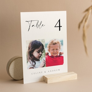 May include: Table number four with a white background and a black handwritten font. The table number is displayed above two photos of children, a girl and a boy, with the names Celine and Andrew written below the photos.