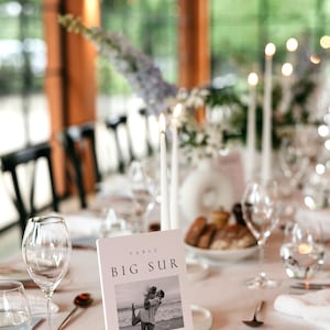 May include: A white table number card with the text "TABLE BIG SUR" and a black and white photo of a couple on a beach. The text below the photo reads "On our third date we took a road trip down to Big Sur. We walked, we laughed, it was a perfect day.  CELINE & ANDREW"