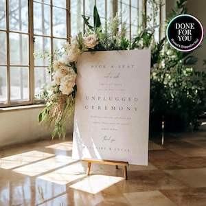 May include: A white rectangular wedding sign on a wooden easel featuring black text that reads Pick a seat not a side, We're all family once the knot is tied, Unplugged Ceremony, Kindly put away your cell phones and cameras, Thank you, Claire & Lucas.