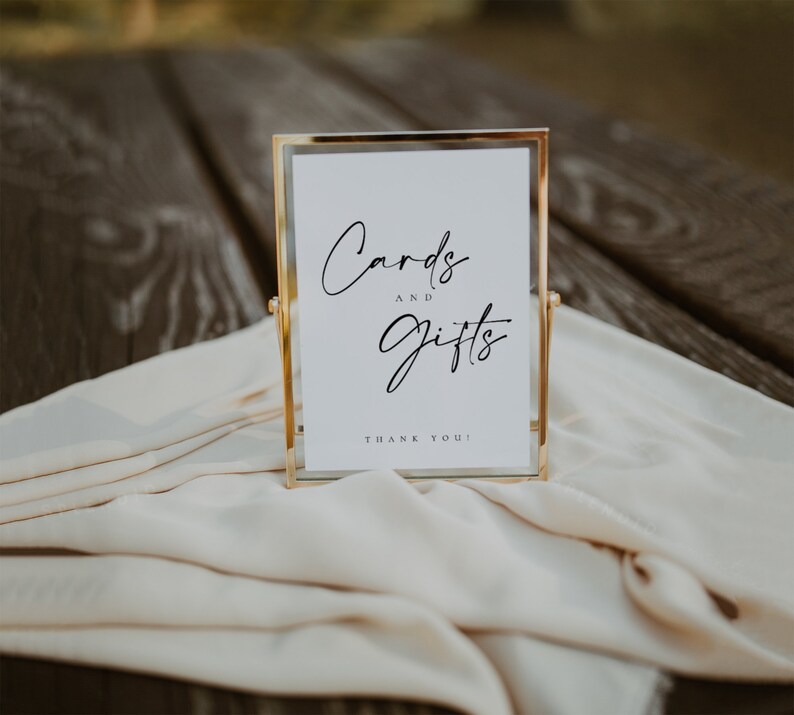 May include: A gold-framed sign with a white background and black text that reads "Cards and Gifts" with the words "Thank You!" at the bottom.