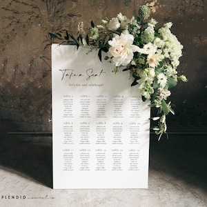 Puede incluir: Un diagrama de asientos blanco con el texto "Take a Seat let's eat and celebrate!" en la parte superior. El diagrama enumera las mesas con los nombres de los invitados asignados a cada mesa.