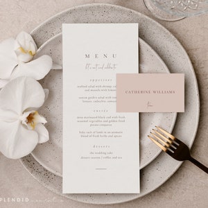 May include: Elegant wedding stationery set featuring a menu card, place card, and gold fork on a speckled plate. The menu reads "MENU" and "Let's eat and celebrate". A white orchid adds a touch of floral elegance.