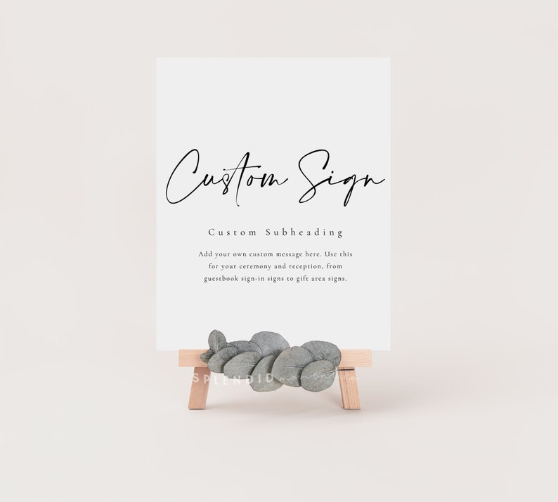 May include: A white sign with black text that reads "Custom Sign" and "Custom Subheading". The text below the subheading reads "Add your own custom message here. Use this for your ceremony and reception, from guestbook sign-in signs to gift area signs."
