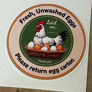 May include: Circular sticker featuring a hen illustration with eggs in a basket. Text reads "Fresh, Unwashed Eggs" and "Please return egg carton". The hen is white with a red comb, set against a green background.