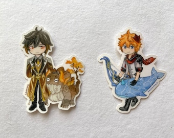 Puede incluir: Dos pegatinas con personajes de estilo anime. Una representa a un personaje con un atuendo dorado y marrón con una criatura. La otra muestra a un personaje con cabello naranja, un arco y una ballena azul. Ambas pegatinas tienen un borde blanco.