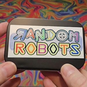 May include: A black rectangular container with the words "RANDOM ROBOTS" in colorful bubble letters. The background is a swirling pattern of rainbow colors.