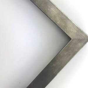 May include: A silver metal picture frame with a beveled edge. The frame is made of a thin metal and has a slightly distressed finish.