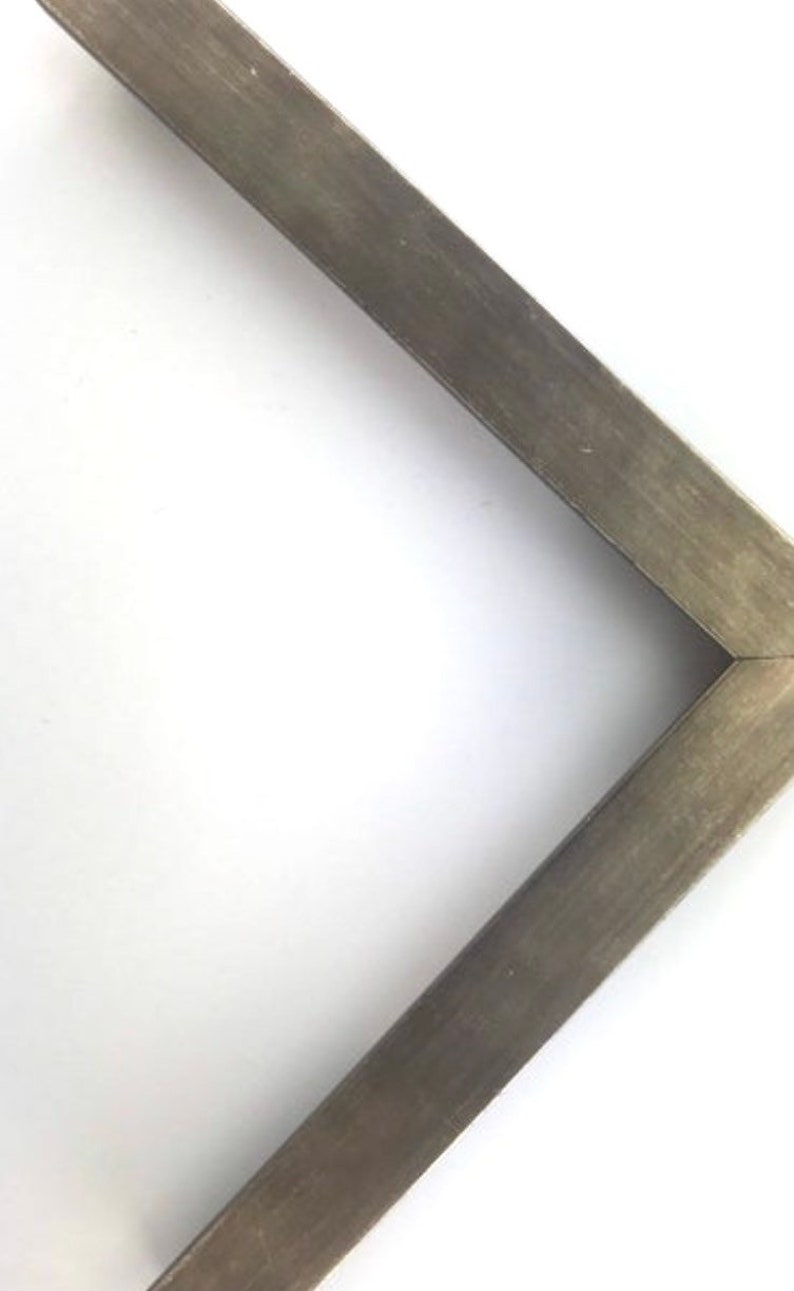 May include: A close-up of a corner of a picture frame with a dark gray wood finish.