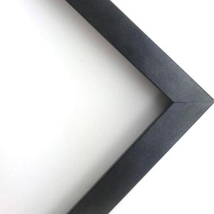 May include: A black picture frame corner with a smooth, matte finish.