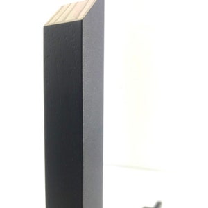 May include: Close-up of the corner of a black wooden frame. The frame is made of solid wood and has a smooth finish.