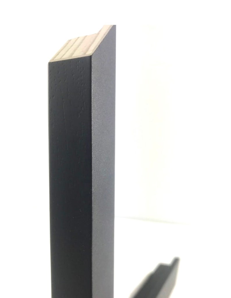 May include: Close-up of the corner of a black wooden frame. The frame is made of solid wood and has a smooth finish.