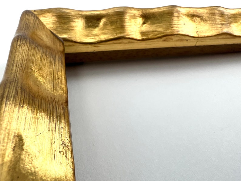 May include: A gold-colored picture frame with a wavy, textured edge.