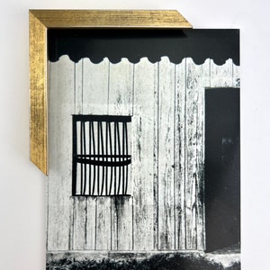Puede incluir: Fotograf&iacute;a en blanco y negro de un edificio con una ventana enrejada y una puerta de madera. El edificio est&aacute; hecho de tablones de madera blanca y tiene una moldura festoneada.
