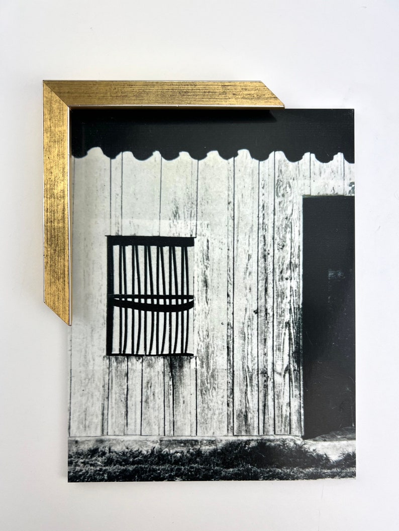 Puede incluir: Fotograf&iacute;a en blanco y negro de un edificio con una ventana enrejada y una puerta de madera. El edificio est&aacute; hecho de tablones de madera blanca y tiene una moldura festoneada.