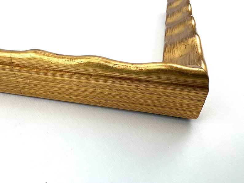May include: Gold picture frame with a wavy, ornate design. The frame is made of wood and has a gold finish.