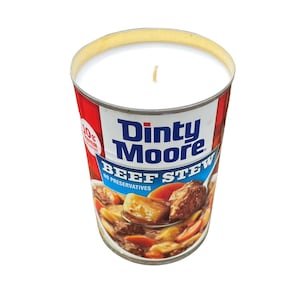 Op de afbeelding: Een witte kaars in een blik Dinty Moore Beef Stew. Het blik heeft een rood, wit en blauw etiket met de tekst "Dinty Moore Beef Stew No Preservatives".