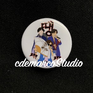 May include: A white button with a cartoon image of three people with the text "FLY" and "B.T.R" on it. The button is on a black background.