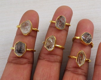 May include: Six gold rings with clear quartz stones. Each ring features a different shaped stone.