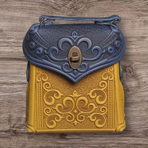 May include: A decorative handbag with a blue top and a yellow body. The bag features ornate embossed designs and a metal clasp. The handle is blue, and the bag has a vintage aesthetic.