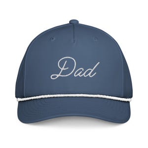 May include: A blue baseball cap with the word "Dad" embroidered in white script. The cap has a white rope detail along the brim.