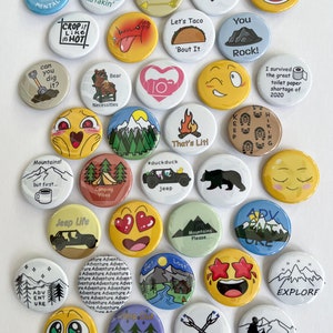 May include: A collection of 25 colorful round buttons with various designs and text related to camping, hiking, and outdoor adventures. The buttons feature images of bears, mountains, jeeps, and other outdoor themes. Some buttons have text such as "Camping Vibes", "Jeep Life", "Mountains! But First...", "Take a Hike!" and "That's Litl".