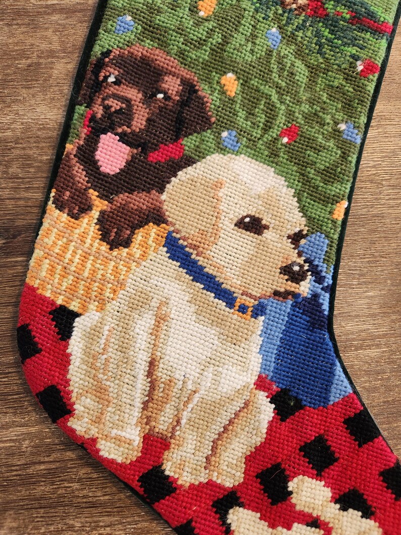 Może przedstawiać: Choinka świąteczna z czerwono-czarną kratą, przedstawiająca dwa psy. Jeden pies to brązowy labrador retriever, a drugi to ż&oacute;łty labrador retriever. Psy siedzą przed zielonym drzewem bożonarodzeniowym z lampkami.