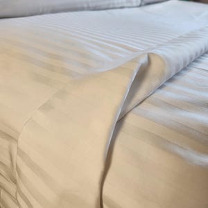 May include: White striped bed sheets with a smooth, wrinkle-free finish. The sheets are made of a soft, comfortable fabric and are perfect for a luxurious sleep experience.