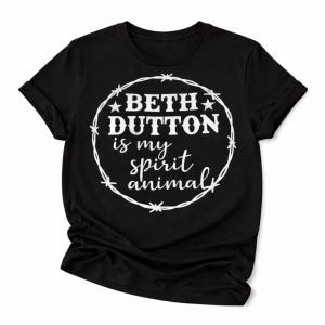 May include: Black t-shirt with the text "BETH DUTTON is my spirit animal" in a white, circular design. The design includes stars and a barbed wire-like border. The shirt is made of a soft material and has rolled-up sleeves.