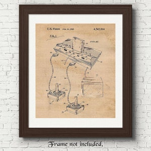 Op de afbeelding: Een zwart-witte patenttekening van een vintage videogameconsole met twee joysticks en een televisie. Het patentnummer is 4.542.014 en de datum is 26 februari 1985. De tekening is op een beige achtergrond.