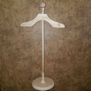 May include: A wooden clothes hanger stand with a round top and a base. The stand is made of natural wood and has a simple design.