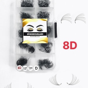 May include: A clear plastic container with eight compartments filled with black eyelash extensions. The container has a label that says "GORGEOUSLASH HANDMADE" and a sticker that says "8D 0.07 12mm D". The container is on a white surface with two pairs of black eyelash extensions.