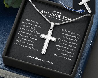 May include: A silver-toned cross pendant on a snake chain, presented in a black gift box. The box insert features the text To My AMAZING SON and a sentimental message. An inset image shows the back of the cross with the text Your Words Here.