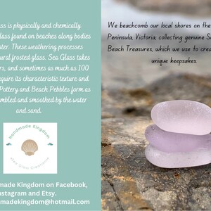 May include: Three pieces of smooth, frosted sea glass in shades of light purple, stacked on top of each other. The sea glass is on a textured, brown surface. The image includes the text "Handmade Kingdom Sea Glass Creations".
