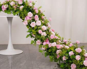 Puede incluir: Una larga guirnalda de rosas rosadas y vegetación, que cae desde una mesa de pedestal blanca. La guirnalda es perfecta para una boda u otro evento especial.