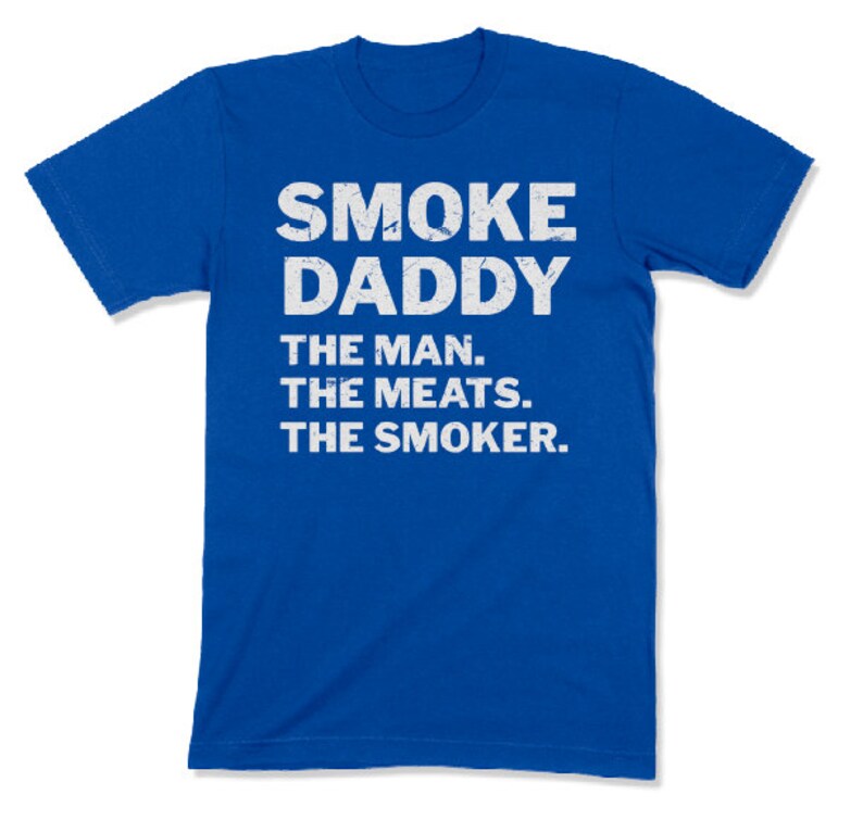 Pu&ograve; includere: Una t-shirt a maniche corte color blu reale con testo bianco in stile consumato che recita: SMOKE DADDY, THE MAN. THE MEATS. THE SMOKER. La maglietta presenta un girocollo e una vestibilit&agrave; standard, con la grafica centrata sul petto.
