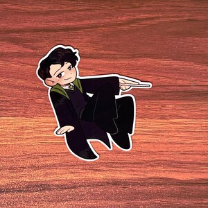 May include: A cartoon illustration of a person wearing a black and green robe with a wand in their hand. The person is in a flying pose.