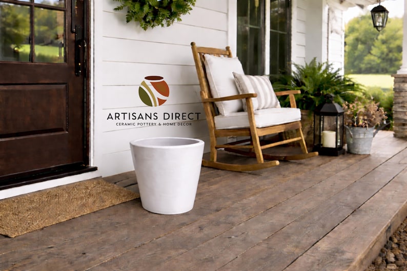 May include: A white ceramic planter sits on a wooden porch. A wooden rocking chair with white cushions and a striped pillow is nearby. The porch has a dark brown door and a welcome mat. The image includes the text "ARTISANS DIRECT CERAMIC POTTERY & HOME DECOR."