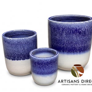 May include: Three ceramic planters in varying sizes. The planters have a two-tone design, with a white base and a speckled blue top. The planters are cylindrical and have a smooth, glossy finish. The logo for Artisans Direct is visible.