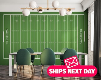 May include: A green and white football field wall decal with the word "TOUCHDOWN" printed on each side. The decal is displayed on a wall in a room with a white ceiling, a wooden floor, and four green chairs around a white table.