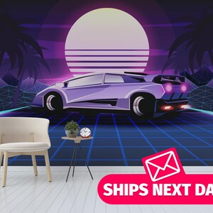 May include: A retro-style wall mural featuring a purple sports car set against a vibrant sunset backdrop with palm trees and geometric mountains. A chair and side table with a plant and clock are in the foreground. The text "SHIPS NEXT DAY" is displayed.
