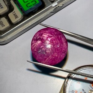 Pode incluir: Uma gema rosa com um padrão de redemoinho, medindo 18 mm de diâmetro.
