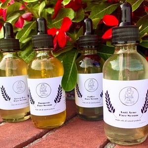 K&ouml;nnte beinhalten: Vier Glasflaschen mit Tropfern, die Gesichts Seren enthalten. Die Flaschen sind mit den Namen der Seren beschriftet: Green Tea Face Serum, Turmeric Face Serum, Coffee Face Serum und Anti Acne Face Serum. Jede Flasche ist mit dem Markennamen "Smooth Like Jas, LLC" beschriftet.