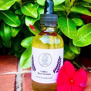 K&ouml;nnte beinhalten: Eine durchsichtige Glasflasche mit schwarzem Tropfer und einem wei&szlig;en Etikett. Das Etikett tr&auml;gt die Aufschrift "Smooth Like Jas, LLC" und "Coffee Face Serum". Die Flasche steht auf einer Ziegelstein-Oberfl&auml;che mit einer rosa Blume.