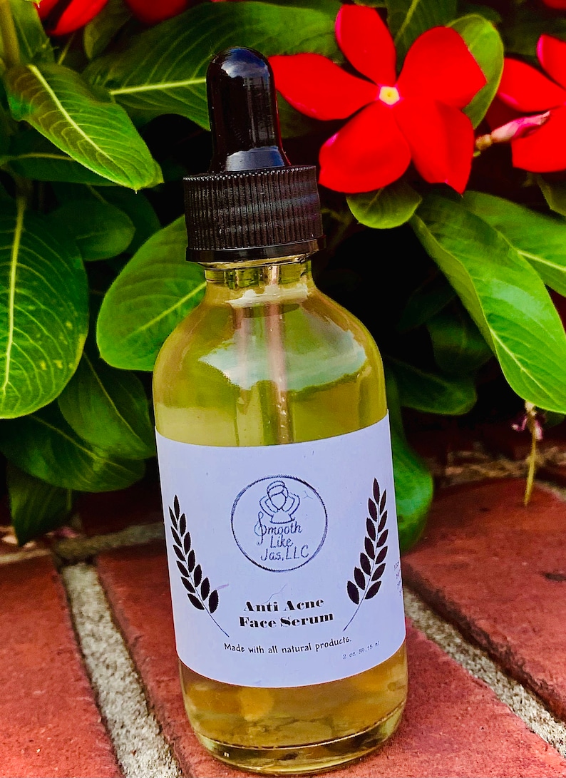 K&ouml;nnte beinhalten: Eine durchsichtige Glasflasche mit schwarzem Tropfer und einem wei&szlig;en Etikett. Das Etikett tr&auml;gt ein Logo mit dem Text "Smooth Like Jas, LLC" und die Worte "Anti Acne Face Serum" mit dem Text "Hergestellt mit nat&uuml;rlichen Produkten. 2 oz (59,14 ml)".